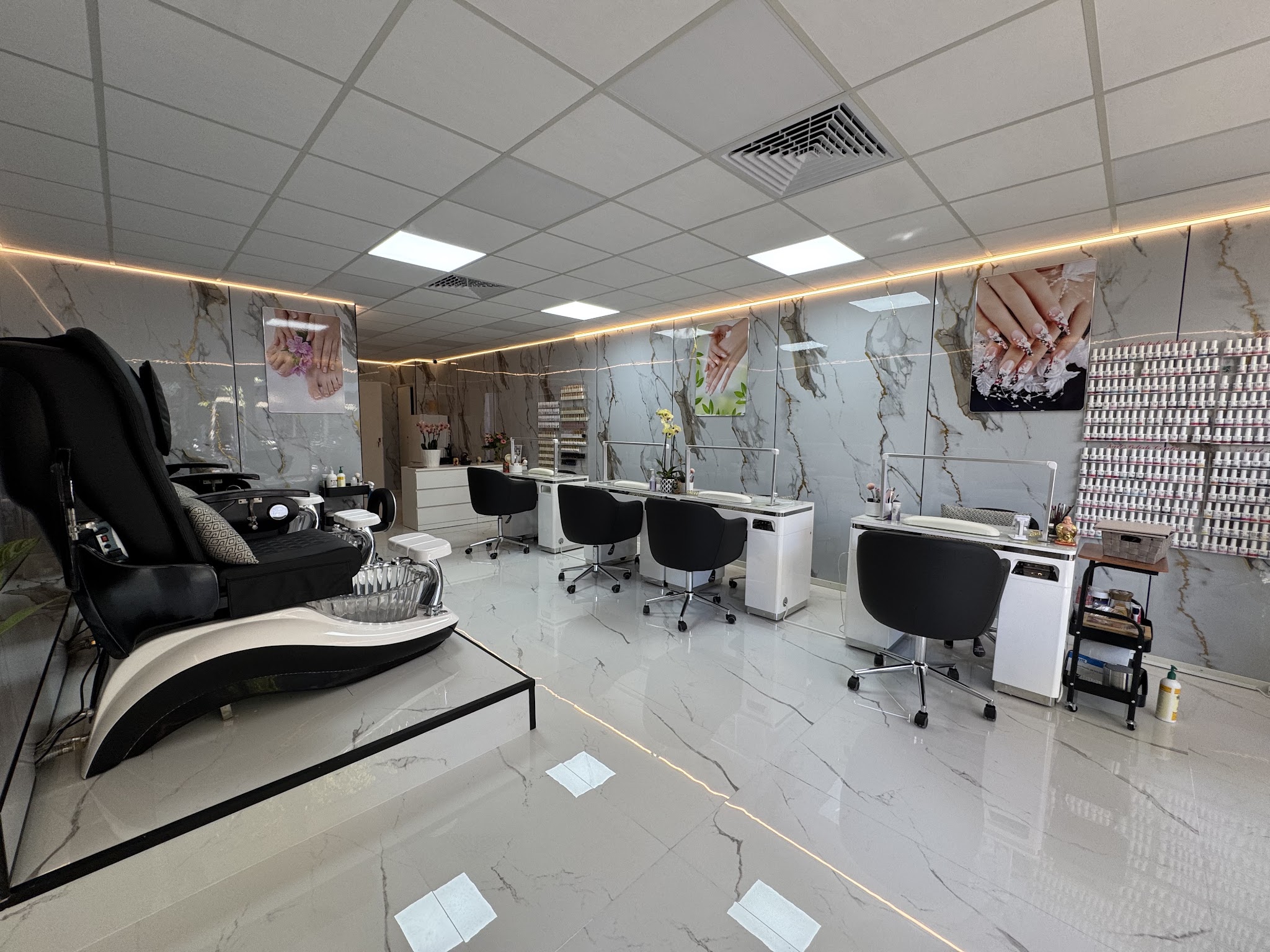 Het interieur van de salon: pedicurestoelen, witte nageltafels en marmeren wanden